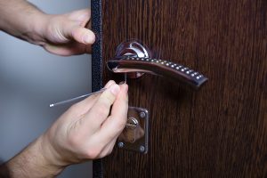 Locksmith replacing door lock to new after losing keys. Robbery protection, safety improvement. Repairman or workman changing or repair door lock.